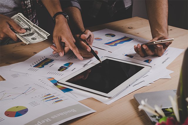 Dos personas analizando una estrategia de marketing digital en una tableta y con graficos.